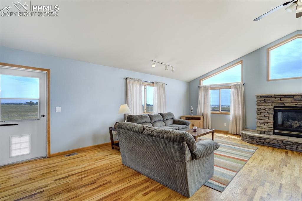 Image 8 of 50: Living area with lofted ceiling, light wood-type flooring, a fireplace, rai