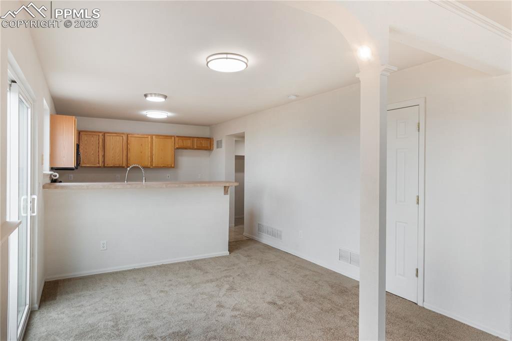 Image 12 of 43: This open-concept area features carpeted flooring, white walls, and a kitch