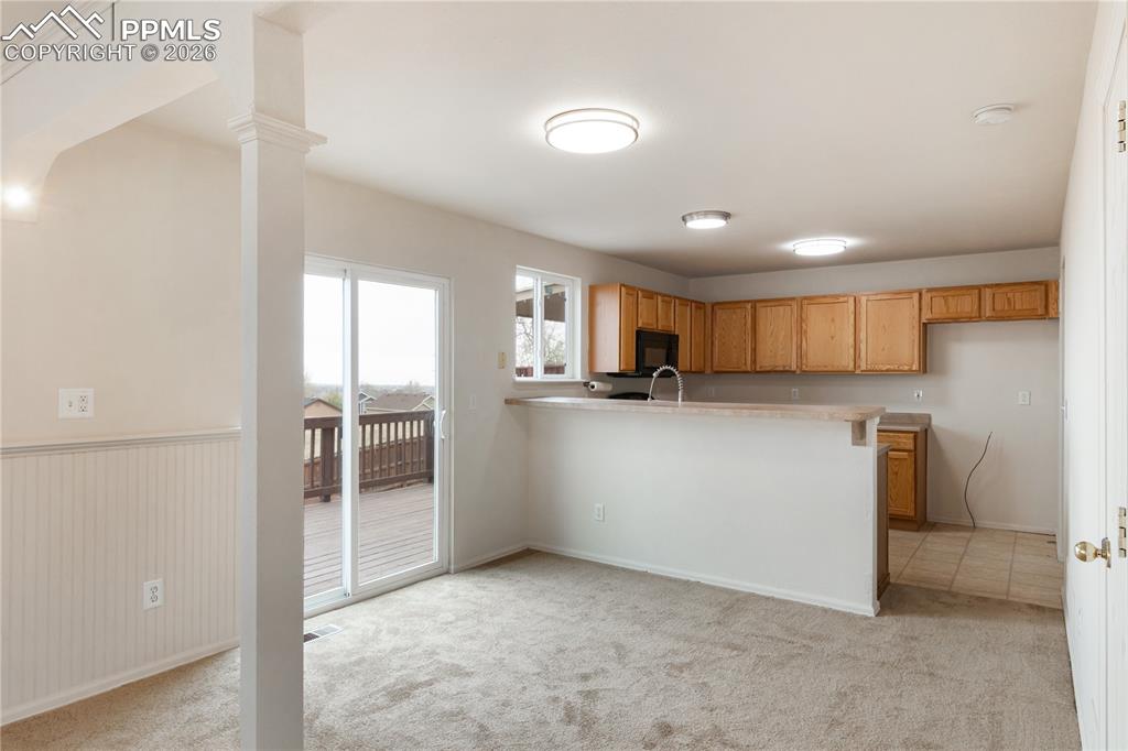 Image 13 of 43: The property features an open-concept living area with carpeting, a kitchen