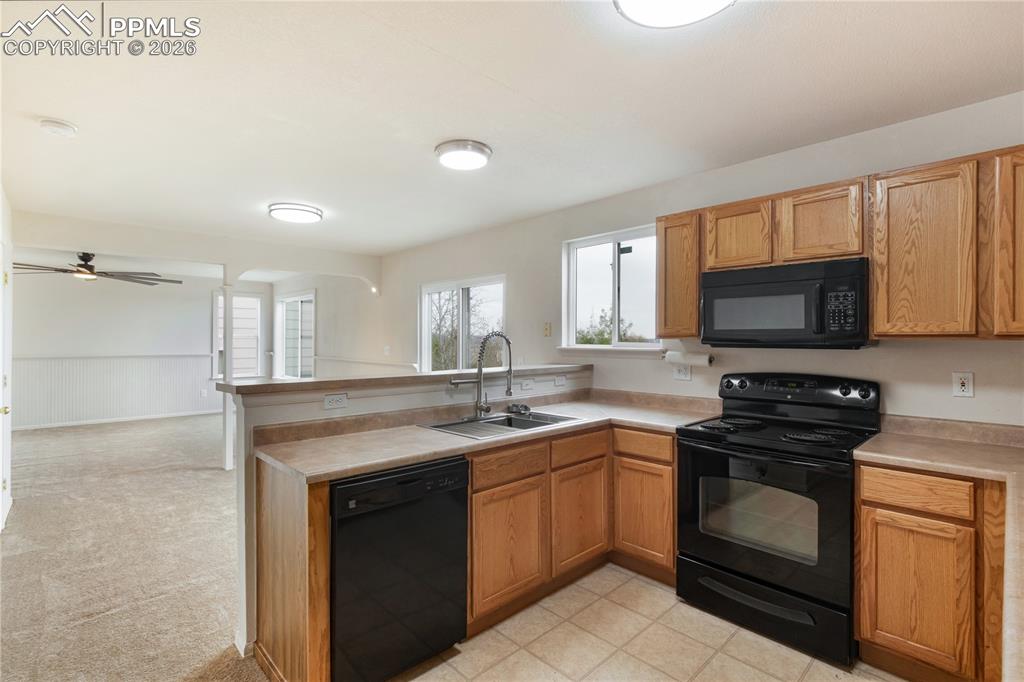 Image 14 of 43: The kitchen features wood cabinetry, a double basin sink with a gooseneck f