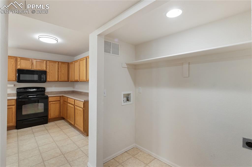 Image 16 of 43: The property features a kitchen with wood cabinetry, a black oven, and a bl
