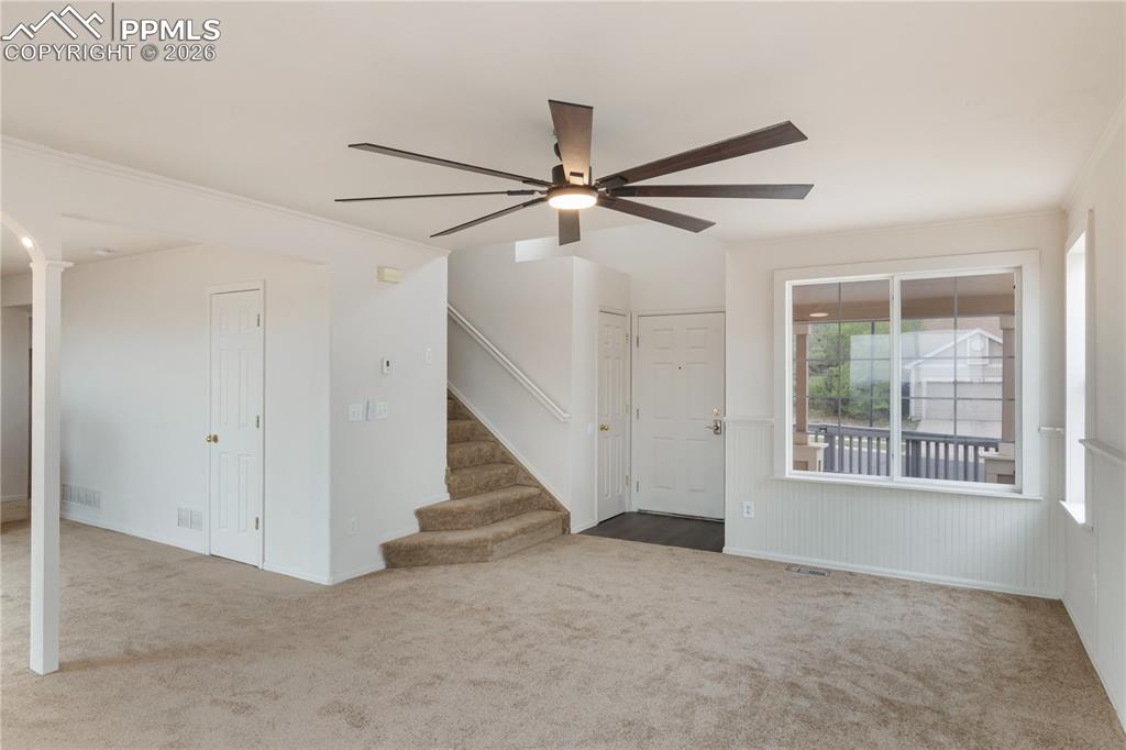 Image 19 of 43: The living area features a modern ceiling fan, carpeted flooring, and white