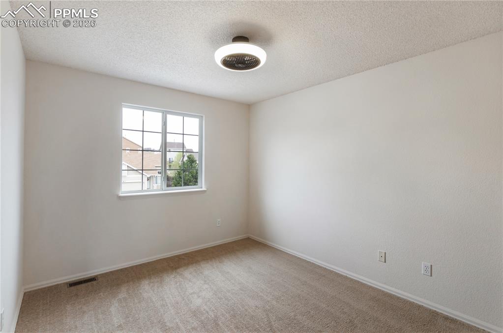Image 21 of 43: The room features neutral-toned carpet, a window with white framing, and a 