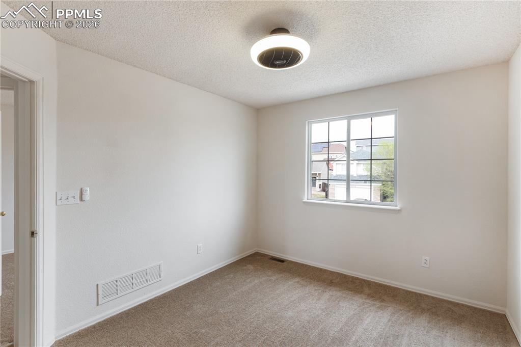 Image 22 of 43: The room features light-colored carpet, a window providing natural light, a