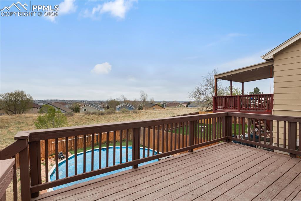 Image 32 of 43: Expansive outdoor decking with railings overlooking a fenced yard and cover