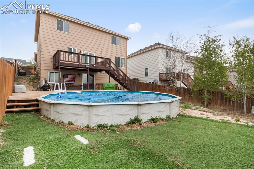 Image 37 of 43: The backyard features a large lawn area, a wooden fence, and an above-groun