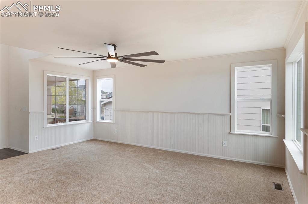 Image 9 of 43: The living area features neutral-toned carpeting, white walls with beadboar