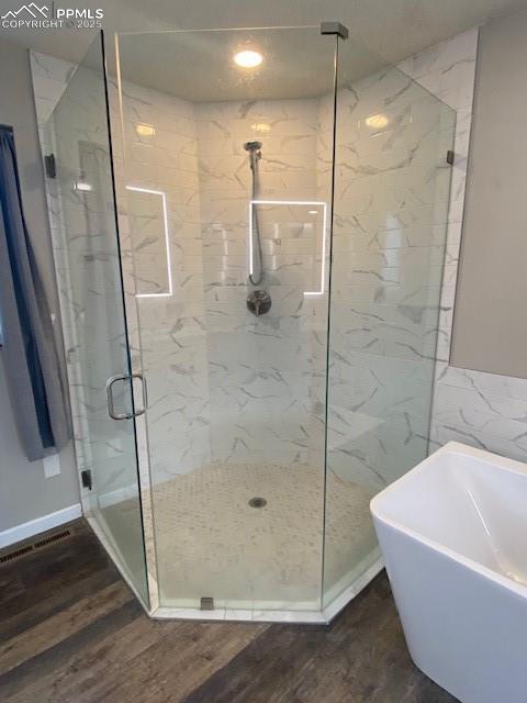 Image 11 of 26: Bathroom with a soaking tub, a marble finish shower, wood finished floors,