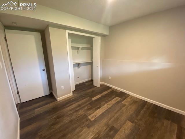 Image 14 of 26: Unfurnished bedroom with dark wood-type flooring, baseboards, and a closet