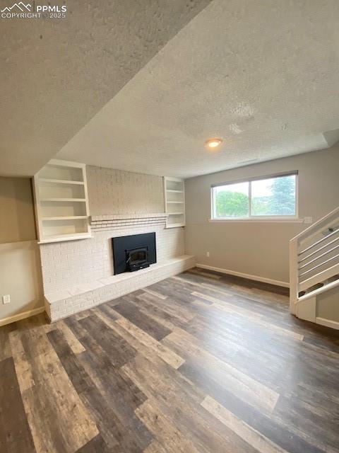 Image 17 of 26: Unfurnished living room featuring a textured ceiling, baseboards, a brick f