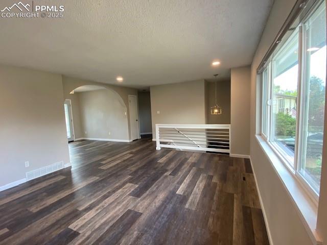 Image 3 of 26: Unfurnished room with dark wood-style flooring, a textured ceiling, baseboa