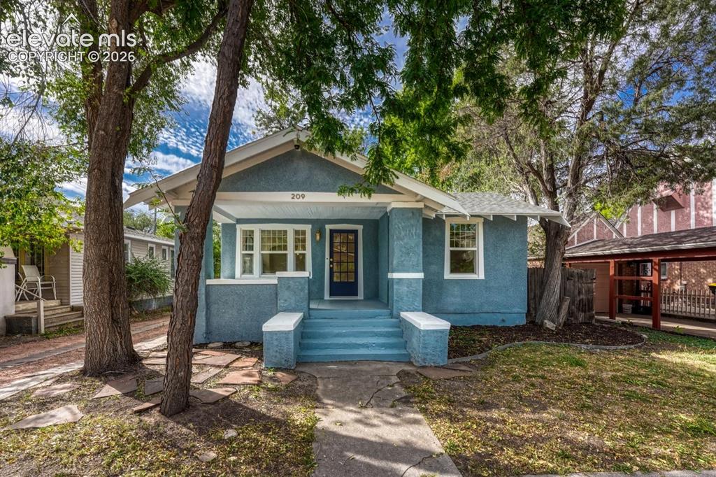Caption: Light blue exterior with white trim, covered front porch, and a dark blue front door