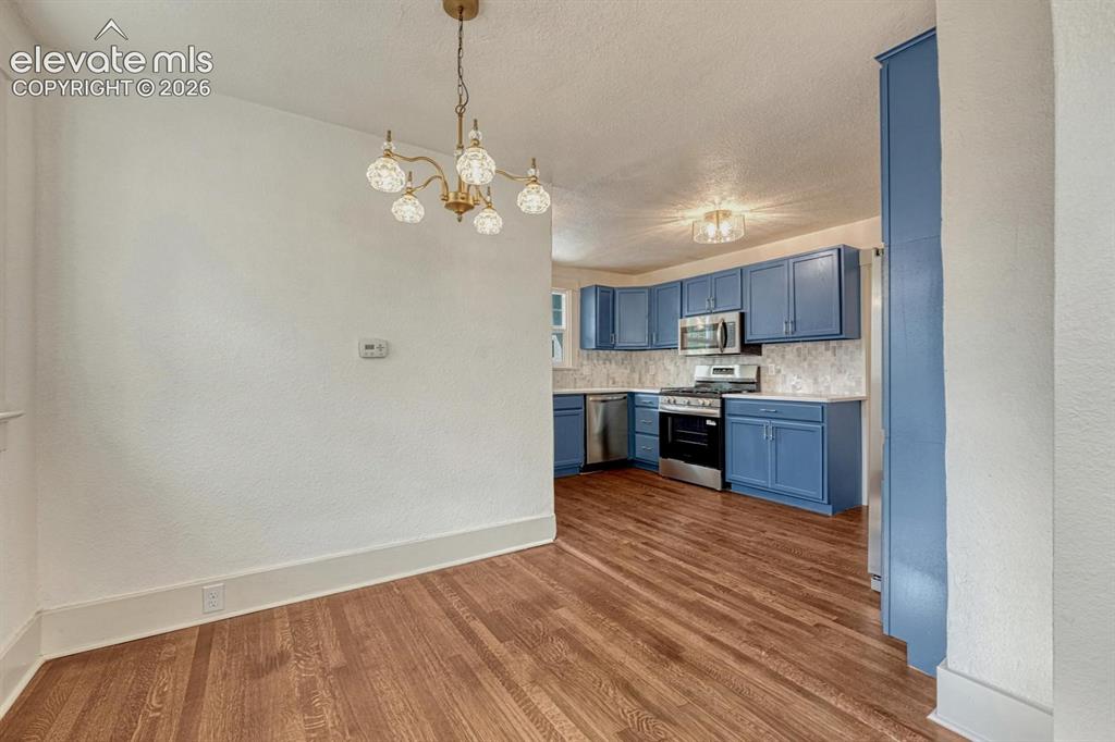 Image 12 of 44: Hardwood flooring throughout, with a brass chandelier, and a kitchen featur