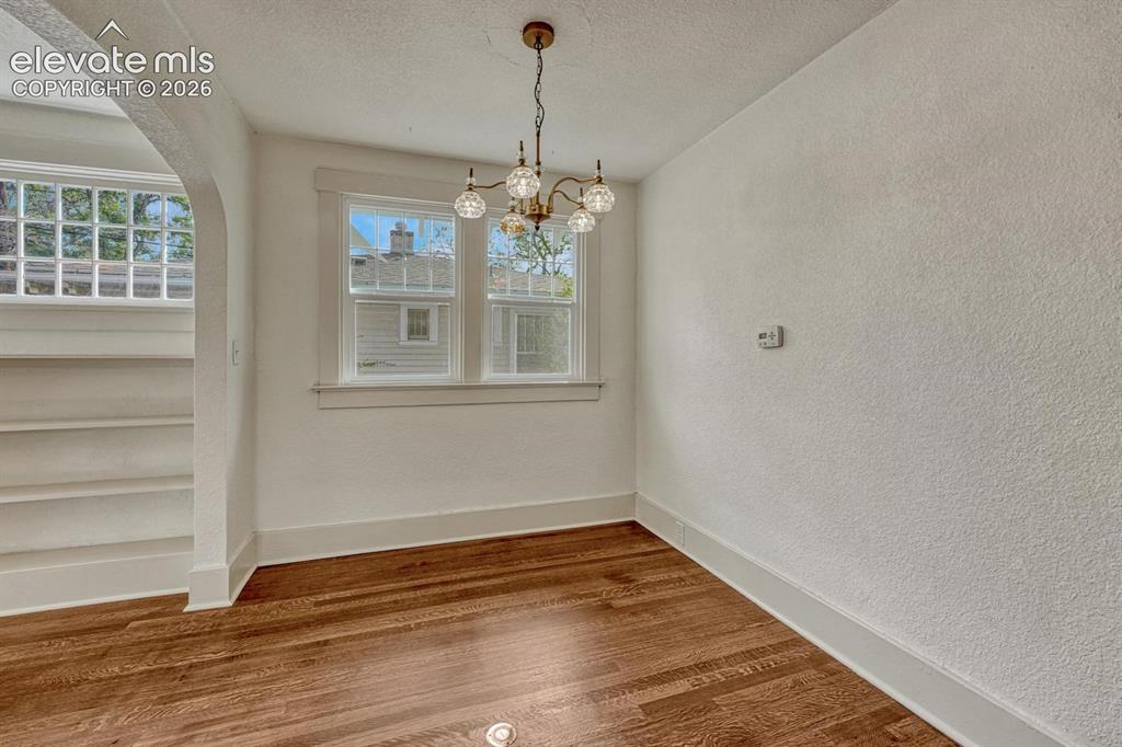 Image 13 of 44: Hardwood flooring, arched doorway, multi-pane windows, brass-finish chandel