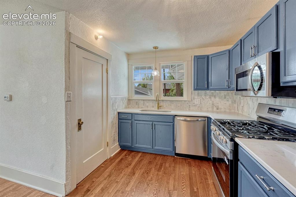 Image 15 of 44: Kitchen featuring blue cabinetry, white countertops, stainless steel applia