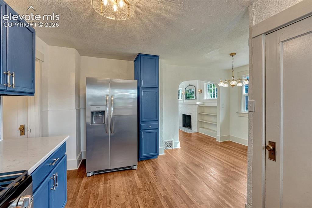 Image 16 of 44: Wood-finish flooring, blue cabinetry with silver-tone hardware, stainless s