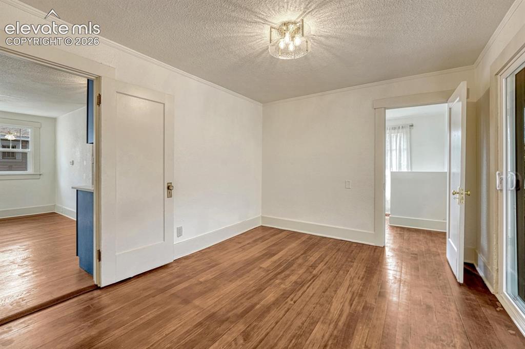 Image 19 of 44: Wood-finish flooring throughout, white trim, crown molding, and a modern se