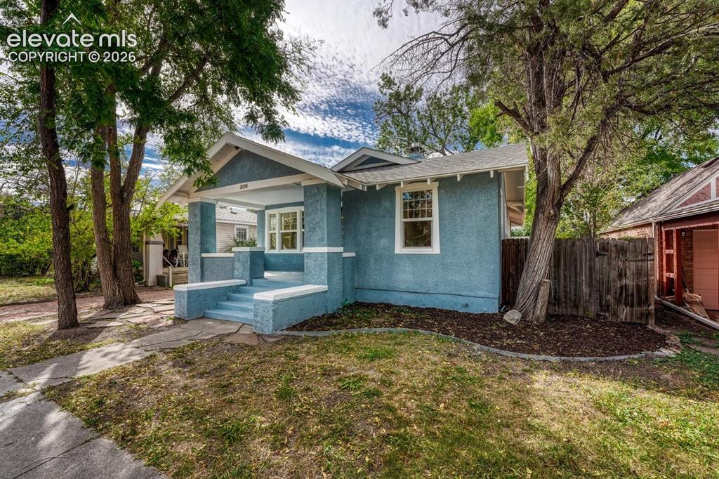 Image 2 of 44: Stucco exterior with a covered porch, white trim detailing, and established