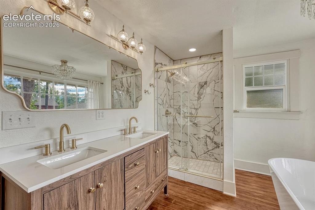 Image 22 of 44: Dual vanity with wood-finish cabinetry, quartz countertop, and brass fixtur