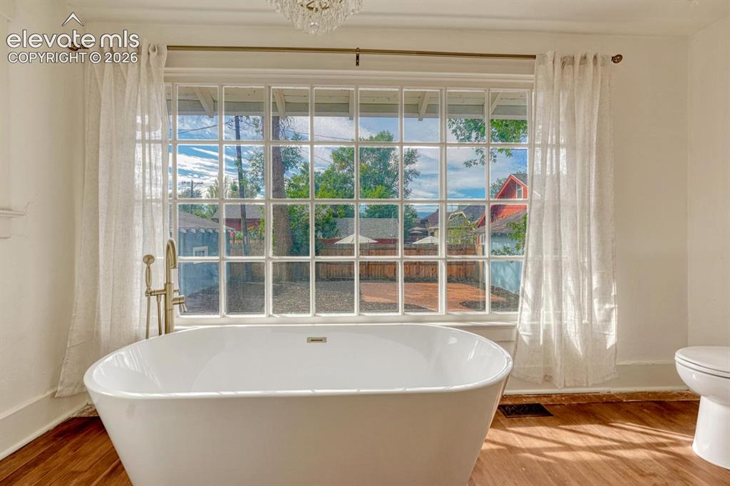 Image 24 of 44: Freestanding soaking tub with a floor-mounted brass fixture, large grid-pat