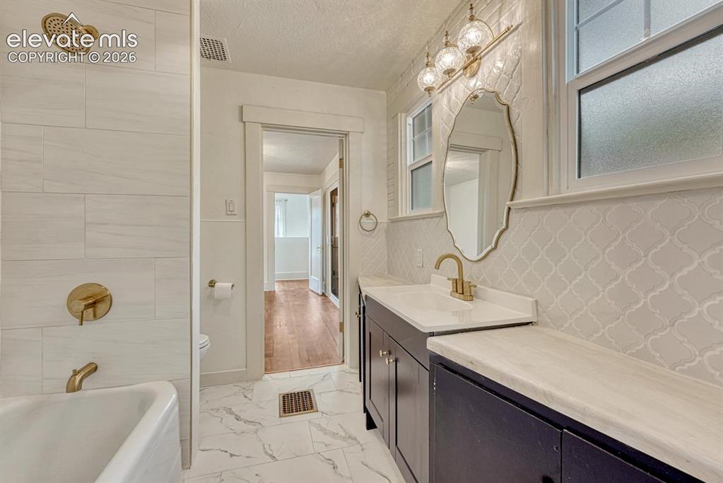 Image 26 of 44: White subway tile shower surround with brass fixtures, a freestanding batht