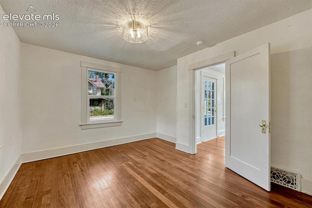 Image 27 of 44: Wood-finish flooring, white trim, and a frosted glass ceiling light fixture