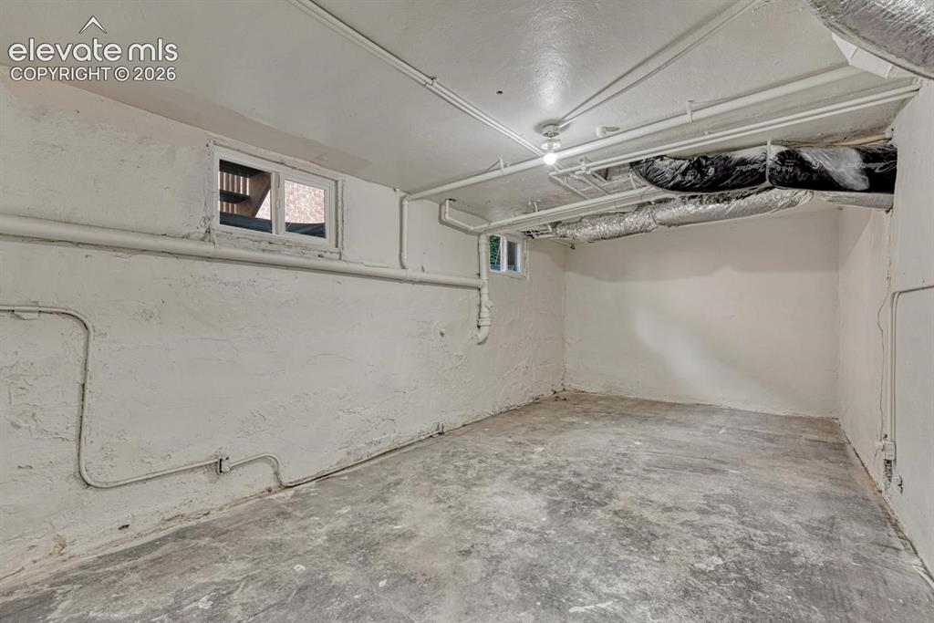 Image 31 of 44: Unfinished basement space with exposed utilities and concrete flooring