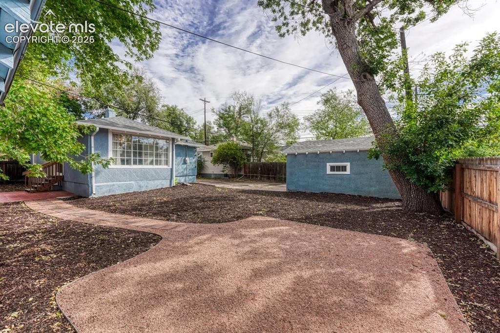 Image 34 of 44: Expansive outdoor space featuring a paved patio area, mature tree, and a de