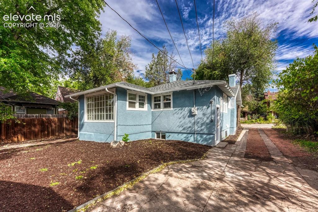 Image 39 of 44: Blue stucco exterior with white trim windows and a light gray shingle roof