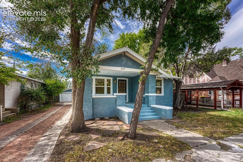 Image 4 of 44: Stucco exterior with a covered front porch, white trim, and a concrete path