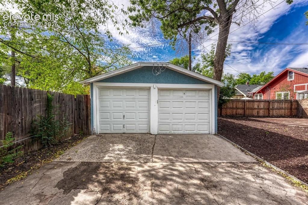 Image 40 of 44: Detached two-car garage with white paneled doors and a blue exterior finish