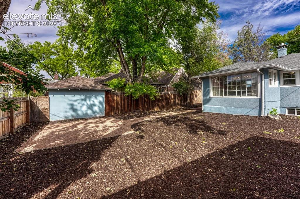 Image 43 of 44: Private backyard featuring wood chip landscaping, a detached structure with