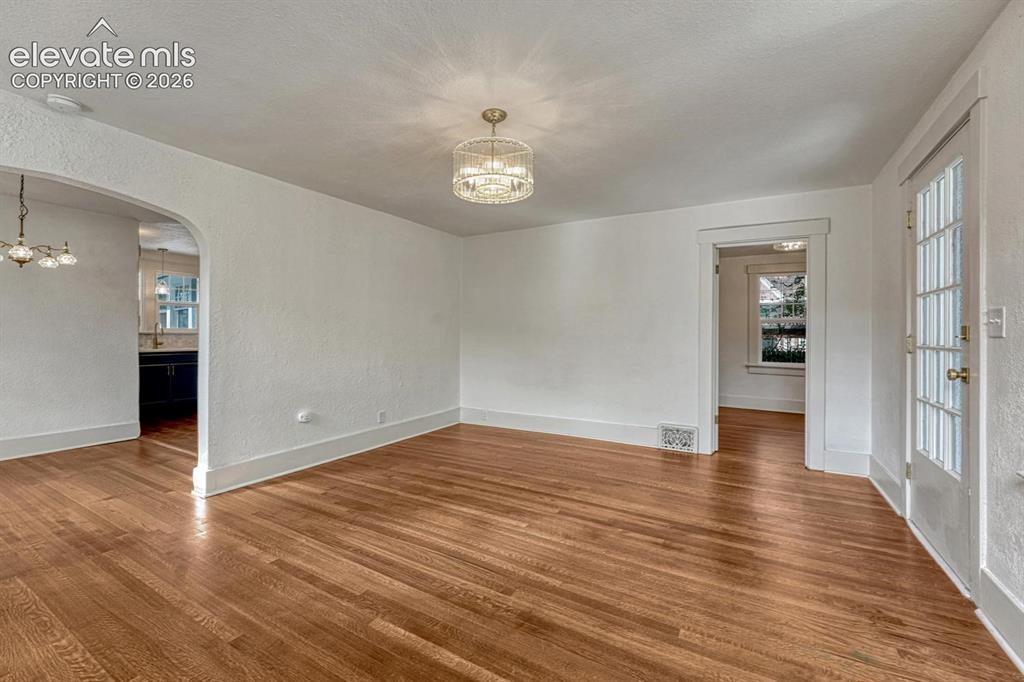 Image 9 of 44: Hardwood flooring throughout, arched doorway, French door with multiple gla