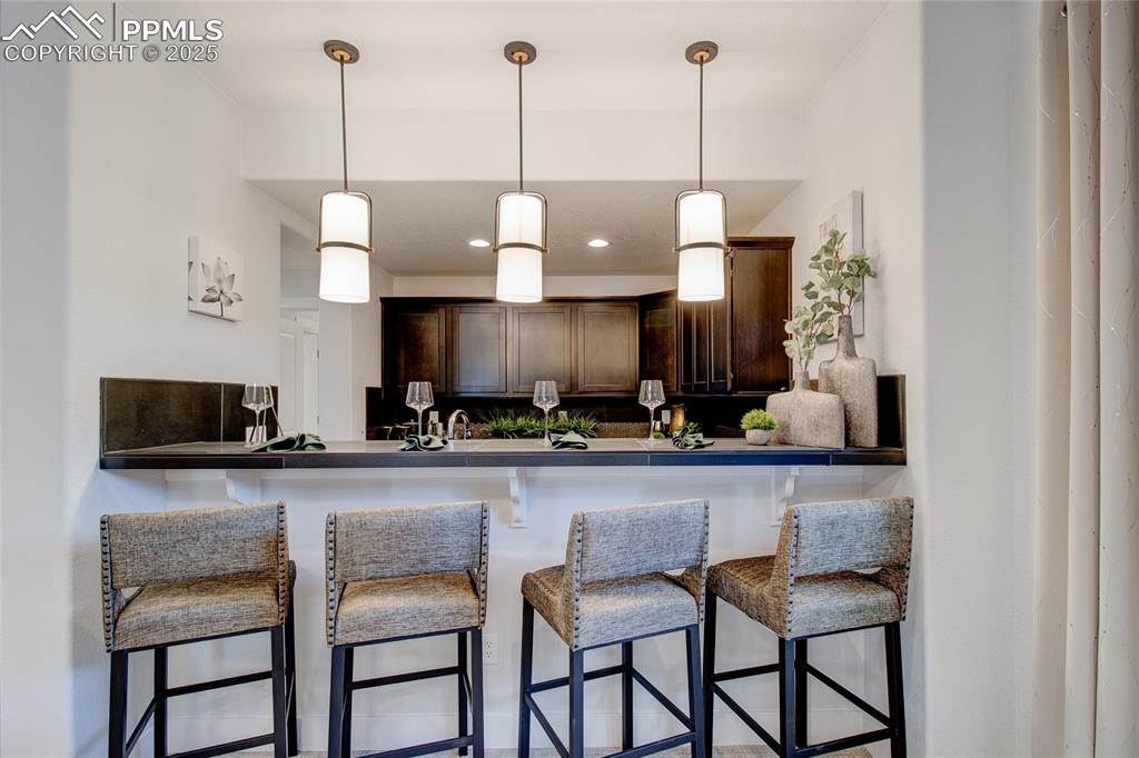 Image 20 of 26: Kitchen featuring dark brown cabinets, pendant lighting, a kitchen bar, dar