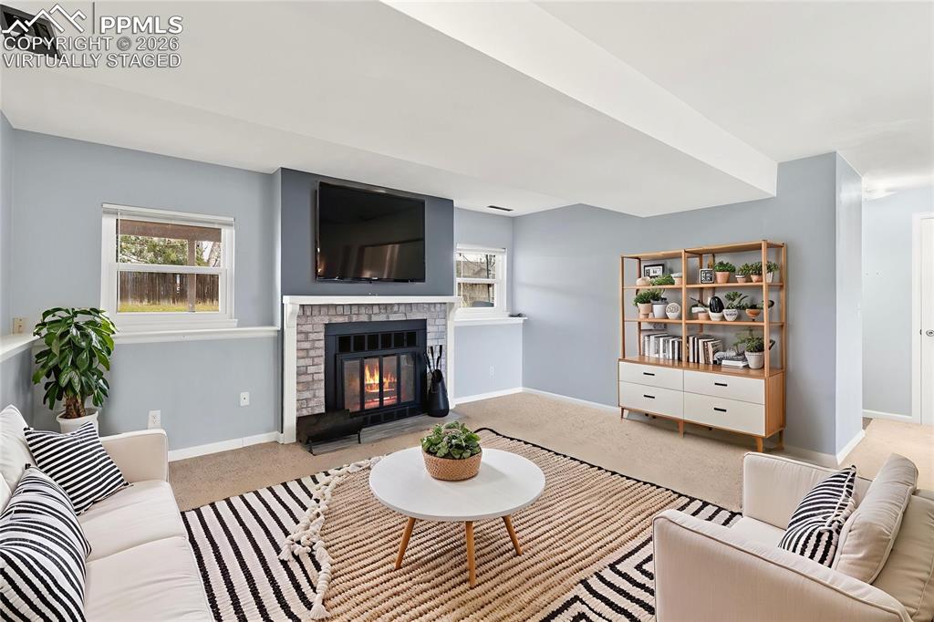 Image 8 of 22: Living room with a brick fireplace and carpet, "Virtually Staged"