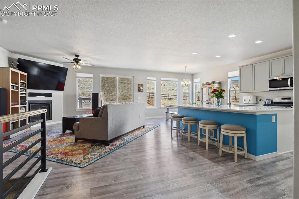 Image 11 of 47: Living area with a ceiling fan, a textured ceiling, a chandelier, recessed