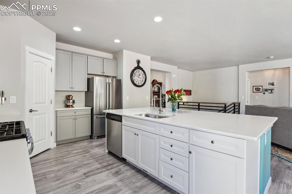 Image 13 of 47: Kitchen with stainless steel appliances, light wood-style floors, light cou