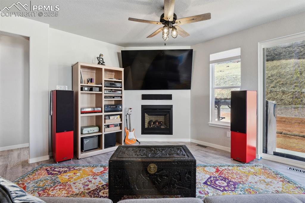 Image 20 of 47: Living room featuring a ceiling fan, a fireplace, and wood finished floors