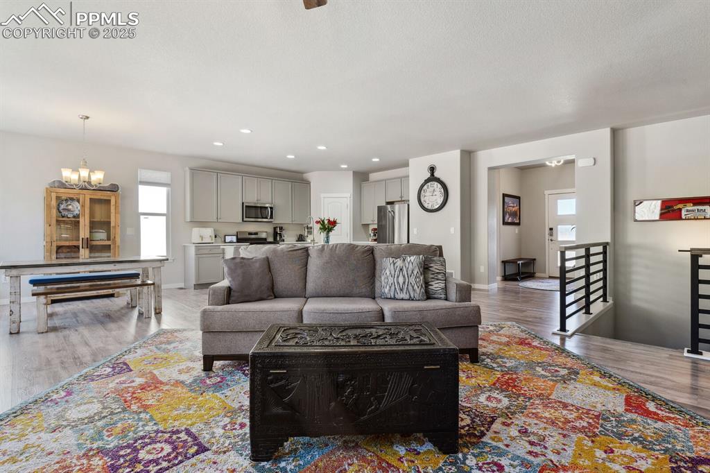 Image 21 of 47: Living room with a chandelier, wood finished floors, and recessed lighting