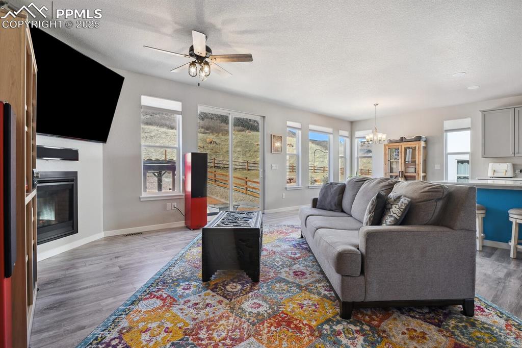 Image 22 of 47: Living area featuring a chandelier, a ceiling fan, light wood-type flooring