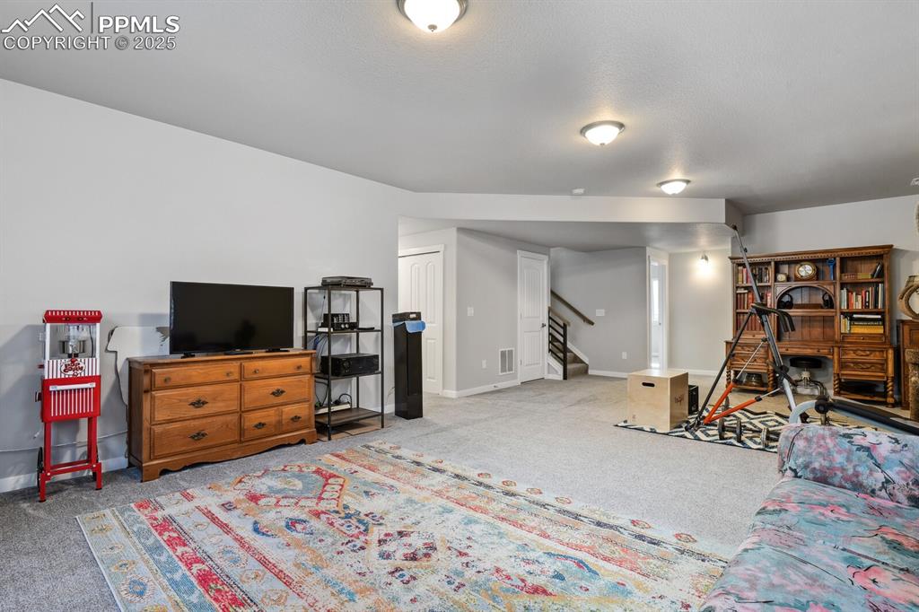 Image 32 of 47: Carpeted living area featuring stairs and baseboards