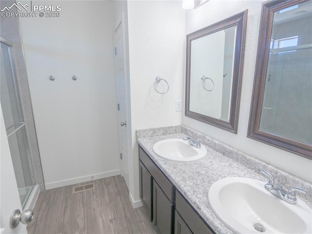 Image 10 of 30: Dual vanity with granite-finish countertop and dark wood cabinetry