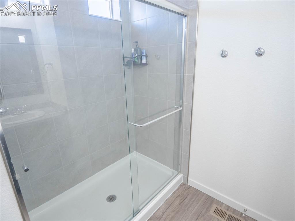 Image 11 of 30: Glass-enclosed shower with light gray tile surround and white shower pan