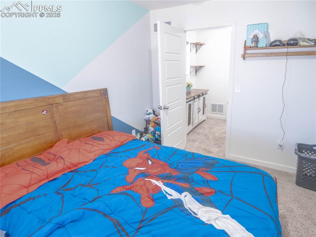 Image 17 of 30: Bedroom featuring a wood-finish headboard and textured wall accents