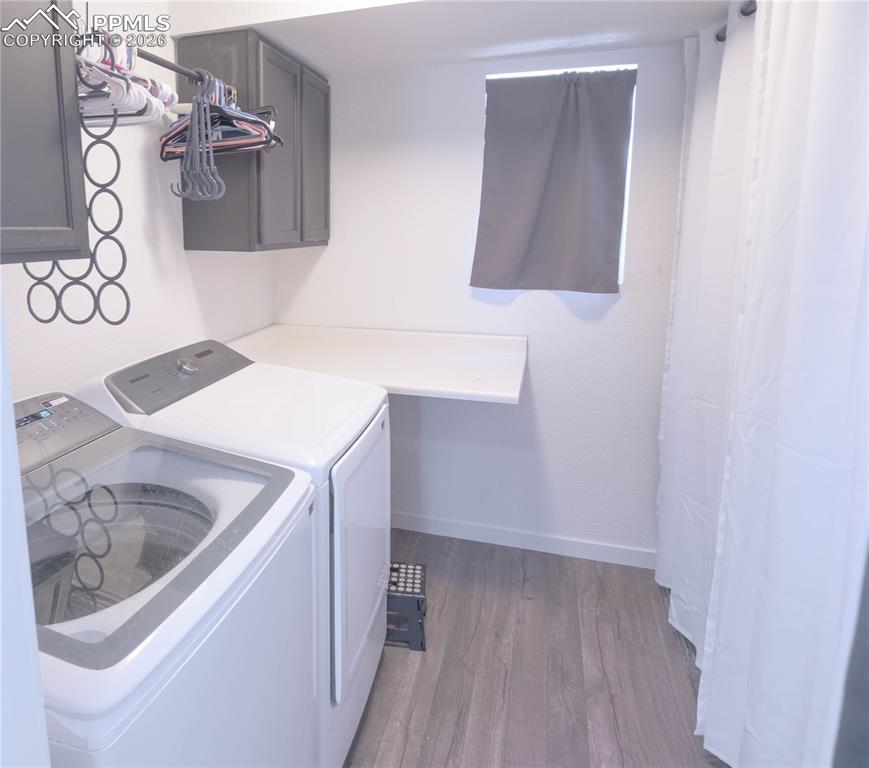 Image 18 of 30: Laundry area with wood-finish flooring, white walls, and a window featuring
