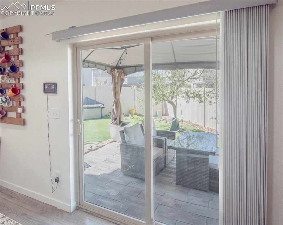 Image 23 of 30: Sliding glass door opening to a private patio featuring stone pavers and a 