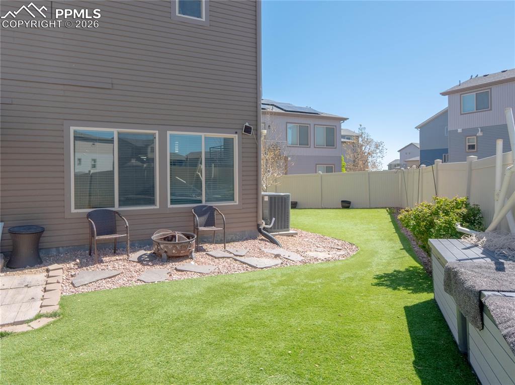 Image 26 of 30: Fenced backyard featuring artificial turf, a rock-covered patio area, and m