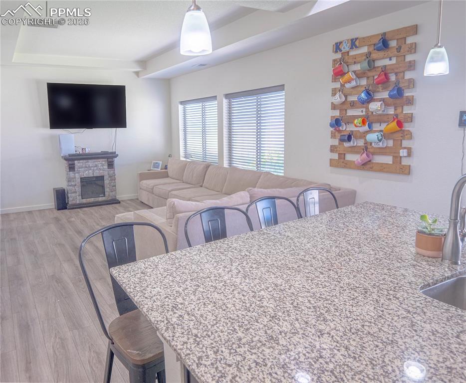 Image 4 of 30: Open-concept living space with wood-finish flooring, recessed tray ceiling,