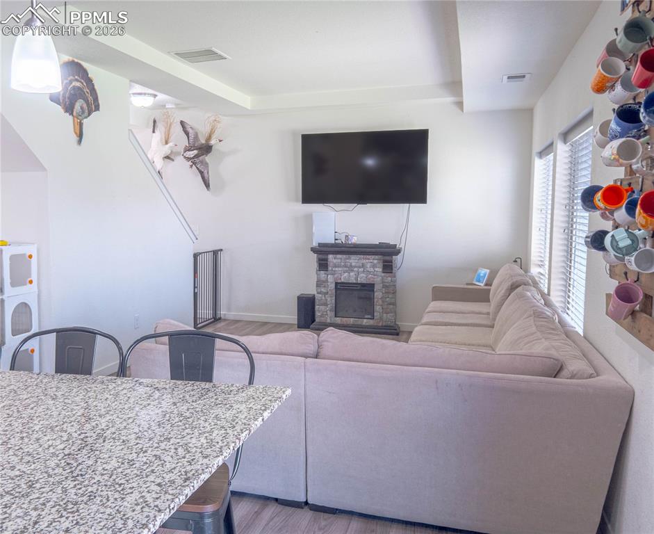 Image 5 of 30: Living area featuring wood-finish flooring and a stone-clad fireplace
