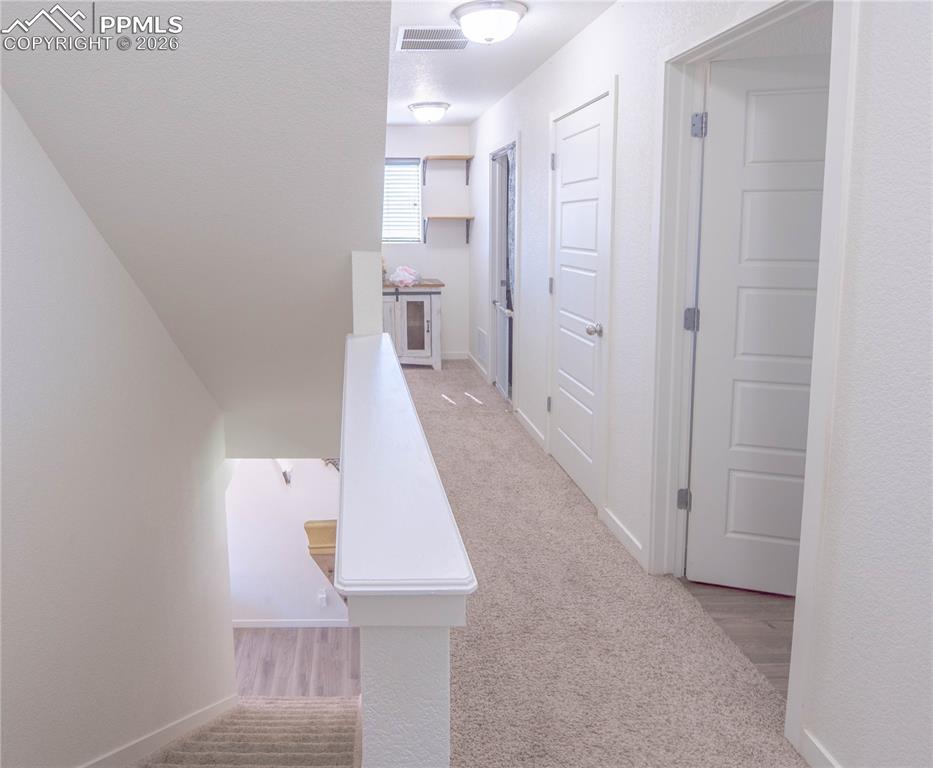 Image 7 of 30: Upper-level landing featuring neutral carpeting and white interior doors